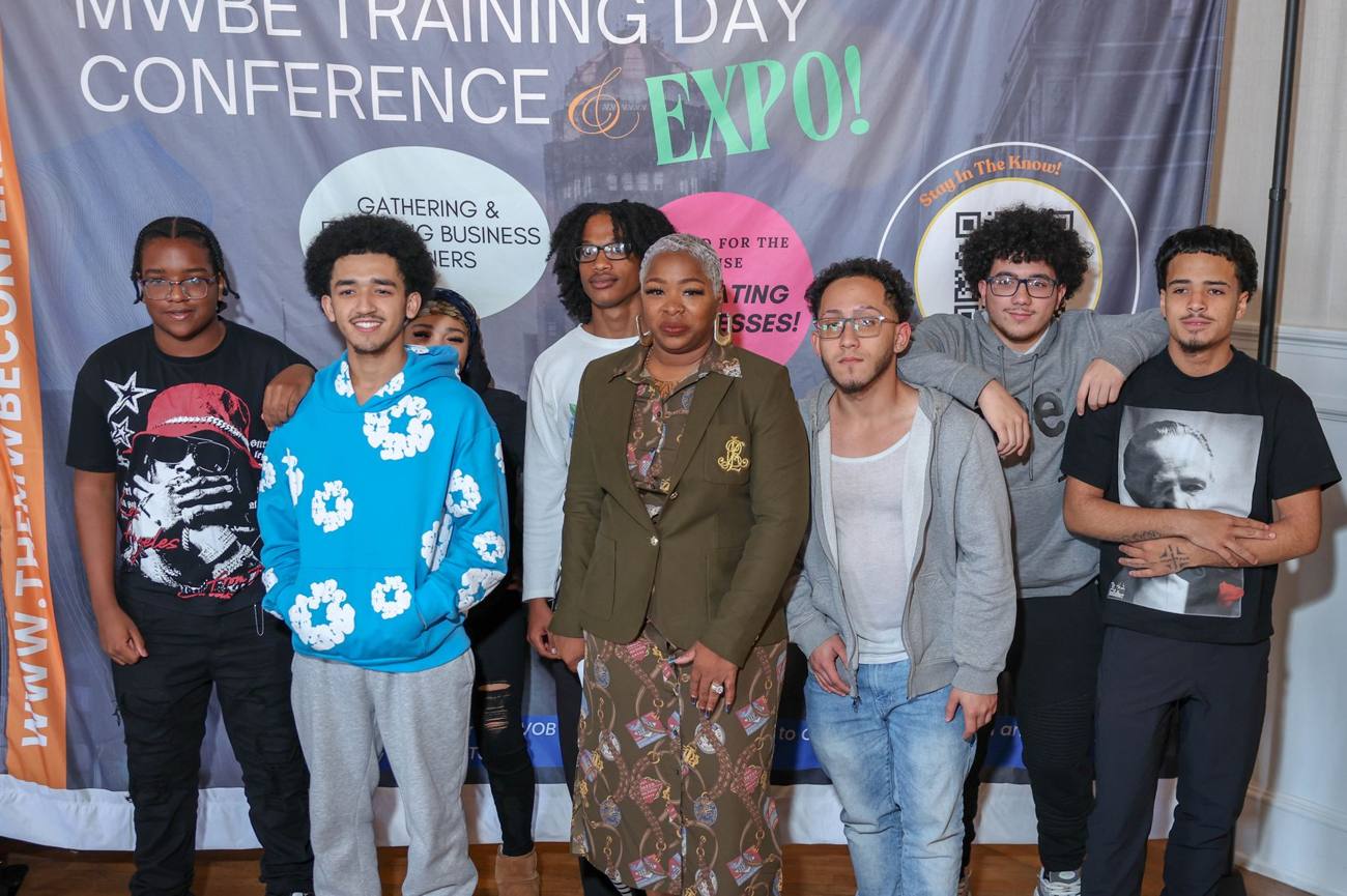 A group of young people with a RARE mentor in front of the conference backdrop