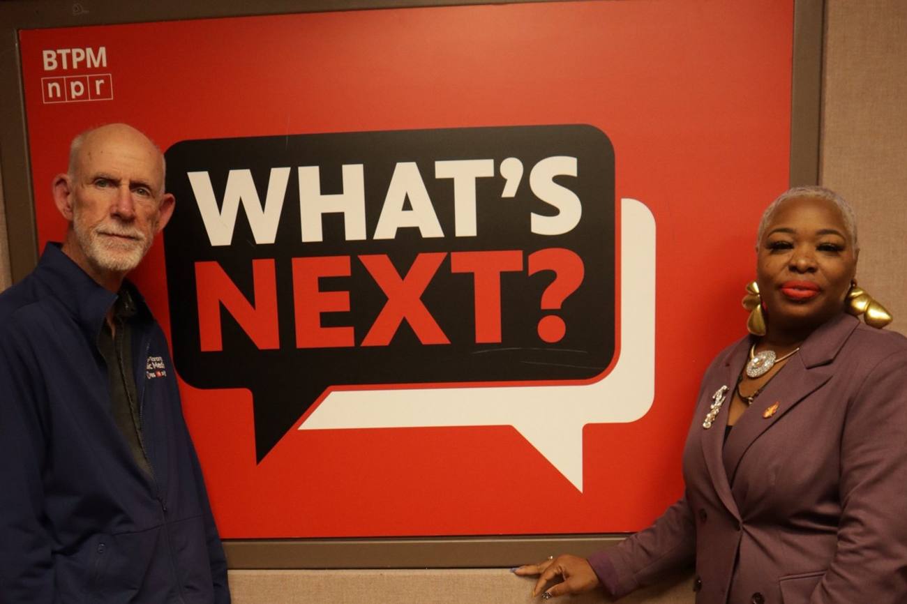 Talia Johnson Huff with the host in the BTPM studio in front of the What’s Next? sign