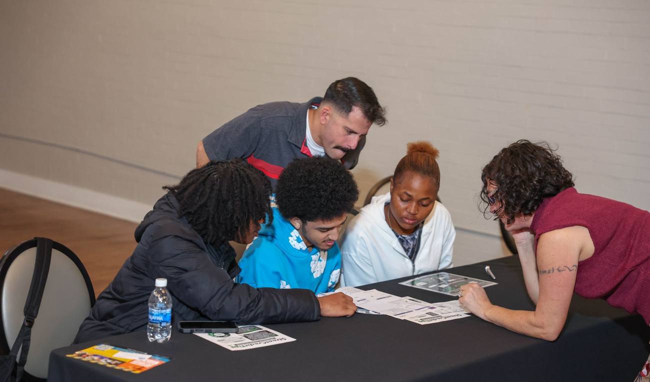 Young people reviewing materials with mentors at a table